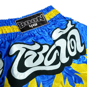 Boon traditional Muay Thai shorts in blue and yellow with bold Thai lettering and elastic waistband