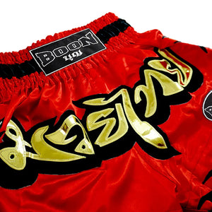 Red Boon Muay Thai shorts with gold Thai lettering, traditional style from Muay Thailand