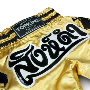 Top King Muay Thai shorts gold satin with black Thai script and branded waistband