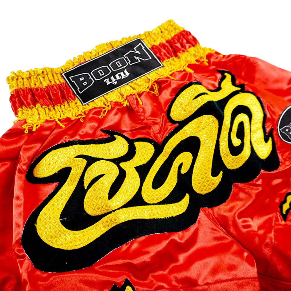 Red and yellow Boon traditional Muay Thai shorts with Thai lettering, Muay Thailand gear