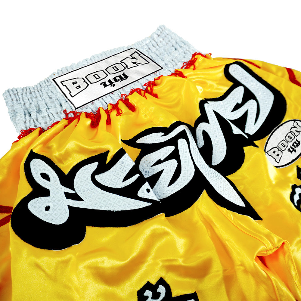 Boon yellow Muay Thai shorts with Thai lettering, red accents, and Boon USA label.