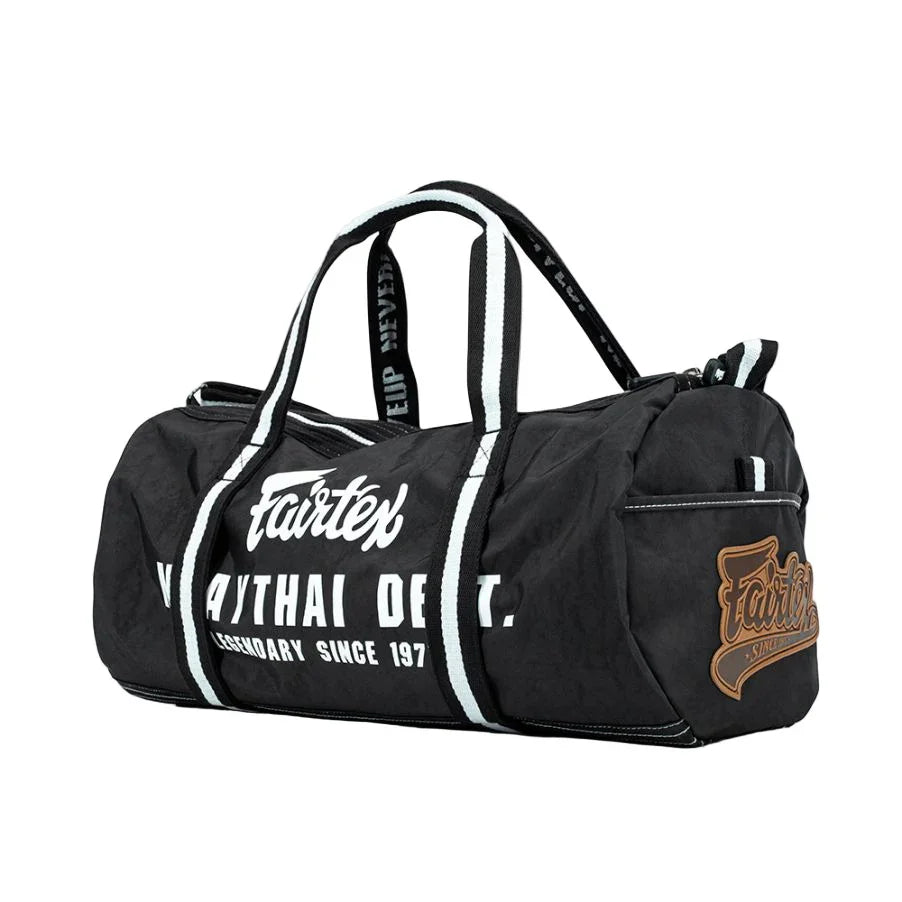 Fairtex black Muay Thai barrel bag with bold white logo and striped handles